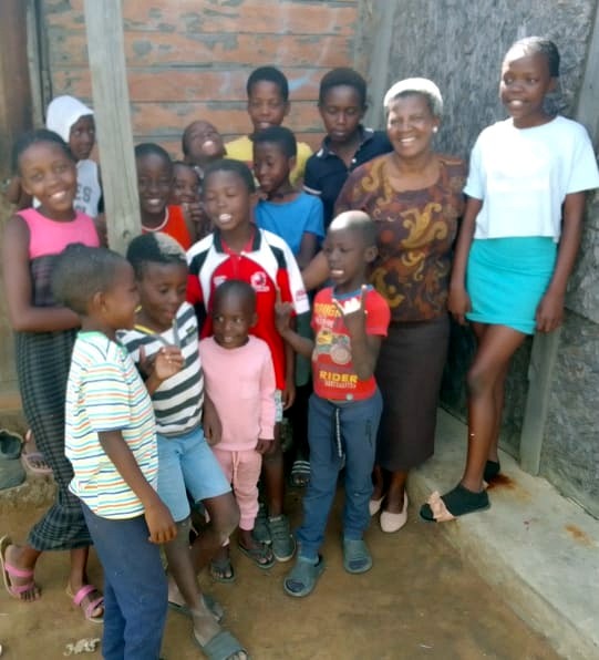Bongi Jele standing with children during a community visit