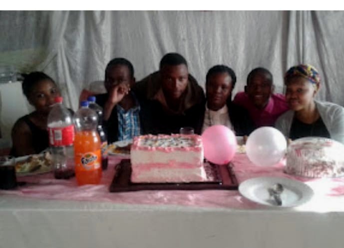 Young people gathered around a celebration cake