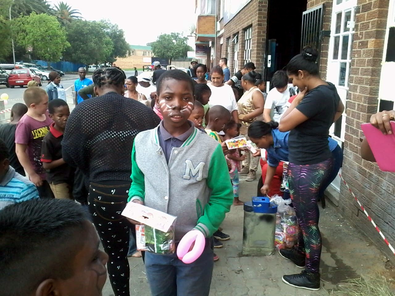 A child receiving items during a busy community giveaway